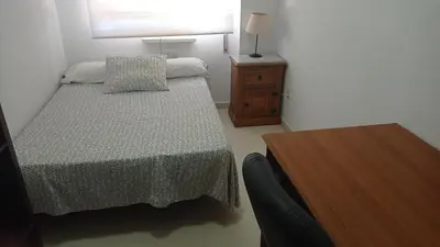 a small bedroom with a bed and a wooden table at Apartamento económico verano 3 DORMITORIOS in El Trocadero
