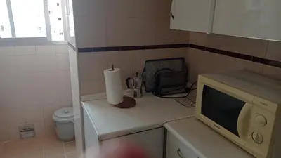 a small kitchen with a microwave and a paper towel at Apartamento económico verano 3 DORMITORIOS in El Trocadero