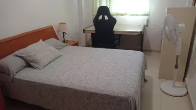 a bedroom with a bed and a desk with a fan at Apartamento económico verano 3 DORMITORIOS in El Trocadero