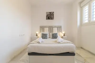 a white bedroom with a large bed with two lamps at Jerez Centro Stay in Jerez de la Frontera