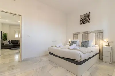 a white bedroom with a large bed and a living room at Jerez Centro Stay in Jerez de la Frontera