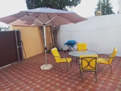 a patio with a table and chairs and an umbrella at Turivivienda La Goleta in Conil de la Frontera