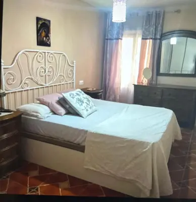 a bedroom with a bed with white sheets and pink pillows at Piso en el centro de sanlucar Bda in Sanlúcar de Barrameda