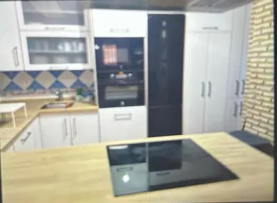 a kitchen with white cabinets and a black appliance at Piso en el centro de sanlucar Bda in Sanlúcar de Barrameda