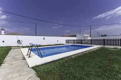 a swimming pool in a yard next to a fence at Casa Mariana in Conil de la Frontera