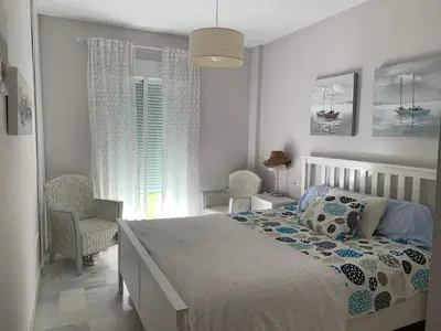a bedroom with a bed and two chairs and a window at Apartamento Las Dunas Costa Ballena in Rota