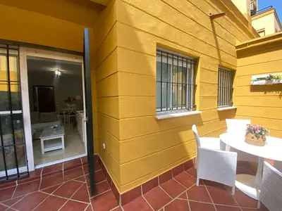 a yellow wall with a table and chairs on a patio at Apartamento Bahía de la Luz in Rota