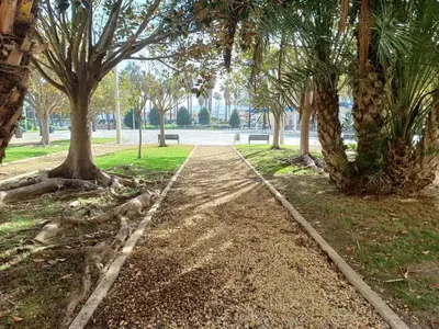 a path in a park with trees and a bench at Apartamento Bahía de la Luz in Rota