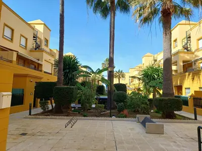 a courtyard with palm trees and a building at Apartamento Bahía de la Luz in Rota