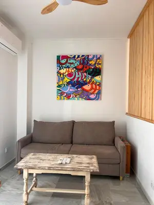 a living room with a couch and a painting on the wall at Estudio Cruz del Mar in Chipiona