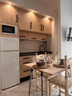 a kitchen with a table and a white refrigerator at Estudio Cruz del Mar in Chipiona
