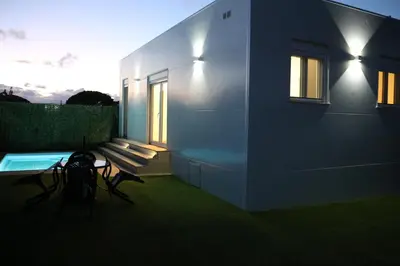 a house with a bench next to a building at La Barrosa Private Suites in Novo Sancti Petri