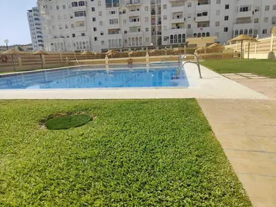 a swimming pool with a grassy area next to a building at GATU Marítimo 