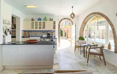 a kitchen with white cabinets and a table and chairs at Stunning Home In Conil De La Frontera in Conil de la Frontera