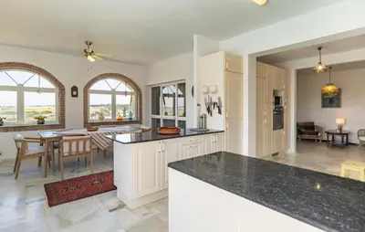 a kitchen with white cabinets and a dining room with a table at Stunning Home In Conil De La Frontera in Conil de la Frontera