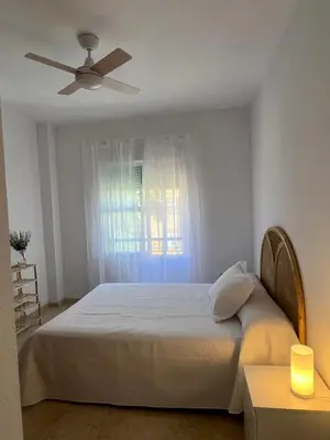 a bedroom with a bed with a ceiling fan and a window at Ático en Costa Ballena in Rota