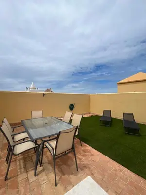 a patio with a table and chairs and grass at Ático en Costa Ballena in Rota