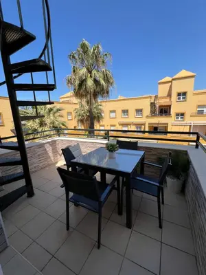 a patio with a table and chairs and a building at Ático en Costa Ballena in Rota