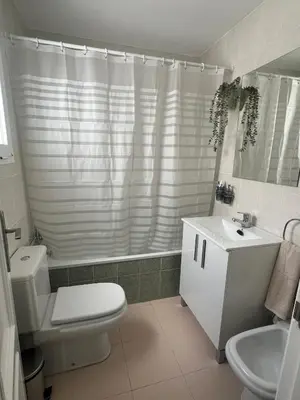 a white bathroom with a toilet and a sink at Ático en Costa Ballena in Rota