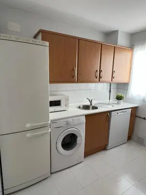 a kitchen with a white refrigerator and a dishwasher at Ático en Costa Ballena in Rota