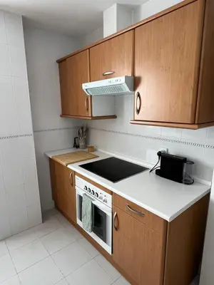 a kitchen with wooden cabinets and a stove top oven at Ático en Costa Ballena in Rota