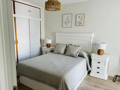 a white bedroom with a bed and two night stands at Mi casa vacacional en Valdelagrana in El Puerto de Santa María