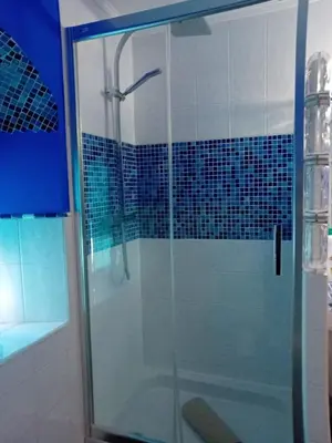 a glass shower in a bathroom with blue tiles at Casa Patricia I in Arcos de la Frontera