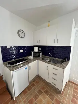 a kitchen with white cabinets and a clock on the wall at Casa Patricia II in Arcos de la Frontera