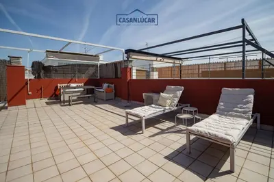 a patio with two chairs and a table on a roof at Atico Molinillo in Sanlúcar de Barrameda