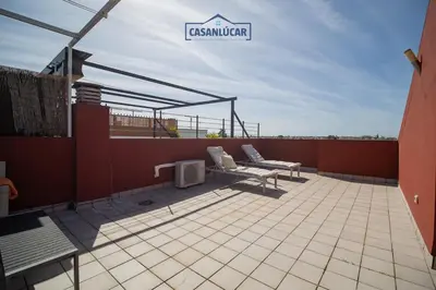 a patio with two benches and a sign on a roof at Atico Molinillo in Sanlúcar de Barrameda