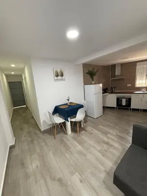a living room with a table and chairs and a kitchen at Apartamento Bf Jerez in Jerez de la Frontera