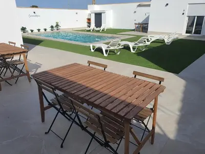 a wooden picnic table and chairs next to a pool at Chiclanafactory in Chiclana de la Frontera