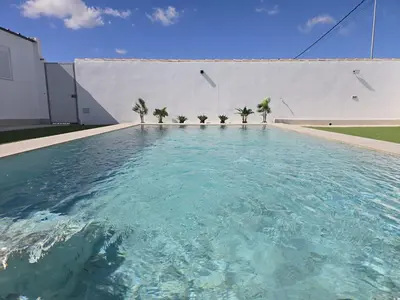 a swimming pool with palm trees in front of a building at Chiclanafactory in Chiclana de la Frontera