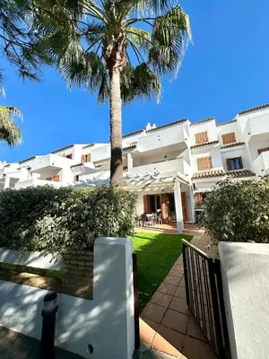 a palm tree in front of a building with a bench at El Ancla in Novo Sancti Petri