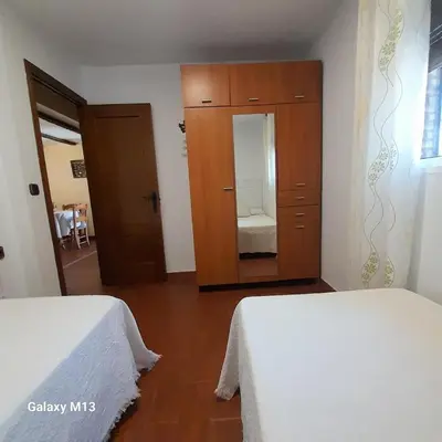 a bedroom with two beds and a cabinet with a mirror at la petit in Chiclana de la Frontera