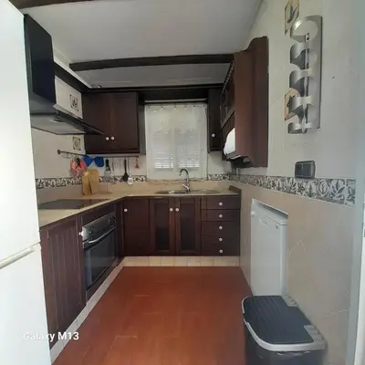 a small kitchen with wooden cabinets and a sink at la petit in Chiclana de la Frontera