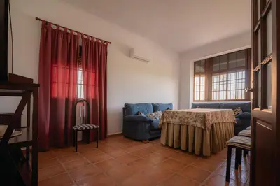 a living room with a table and red curtains at Casa Rural Manuel Sevillano in Bornos