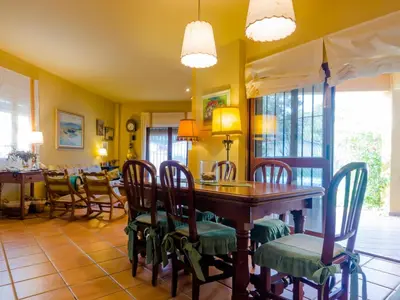 a dining room with a wooden table and chairs at Villa La Vega 14354 in Chiclana de la Frontera