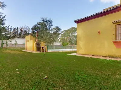 a yard with a yellow building and a fence at Villa La Vega 14354 in Chiclana de la Frontera