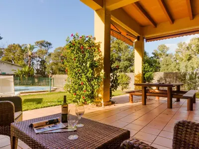 a patio with a table and a bottle of wine at Villa La Vega 14354 in Chiclana de la Frontera