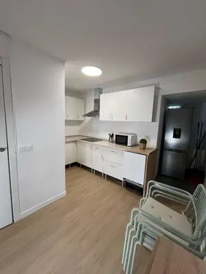 a small kitchen with white cabinets and a refrigerator at Centrally located apartment with terrace in El Puerto de Santa María