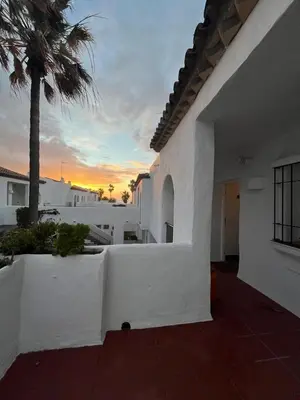 a white building with a palm tree and a sunset at Frente al Mar, Tu Refugio Ideal in Novo Sancti Petri