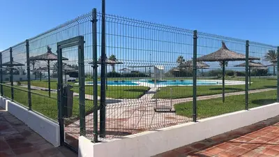 a fence with umbrellas next to a swimming pool at Frente al Mar, Tu Refugio Ideal in Novo Sancti Petri