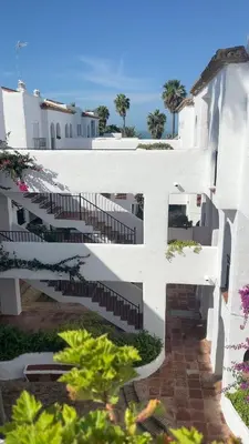a white building with stairs and trees in the background at Frente al Mar, Tu Refugio Ideal in Novo Sancti Petri