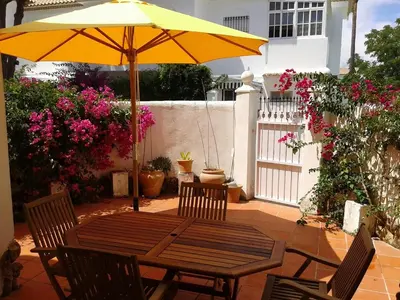 a wooden table with an umbrella on a patio at Residencial Pinar Atlántico in Novo Sancti Petri