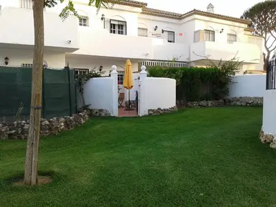 a house with a yard with a fence and an umbrella at Residencial Pinar Atlántico in Novo Sancti Petri