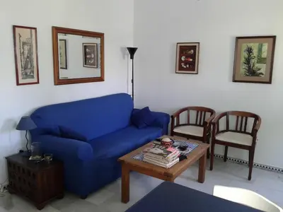 a living room with a blue couch and two chairs at Residencial Pinar Atlántico in Novo Sancti Petri