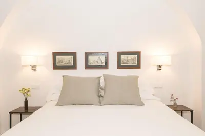 a bedroom with a white bed with three pictures on the wall at Mar Abierto B in Sanlúcar de Barrameda