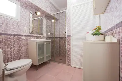 a bathroom with a toilet and a shower with pink tiles at Casa Algodon in Chiclana de la Frontera