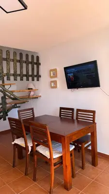 a dining room table with chairs and a television on a wall at Dúplex tras Regla in Chipiona